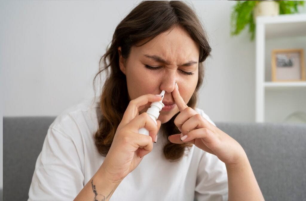 front view woman using nasal spray 1 Dra Camilla Ferreira - Otorrino